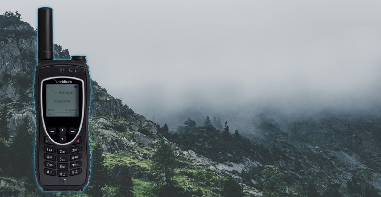 Iridium 9575 Extreme satellite phone against a misty forested mountainside